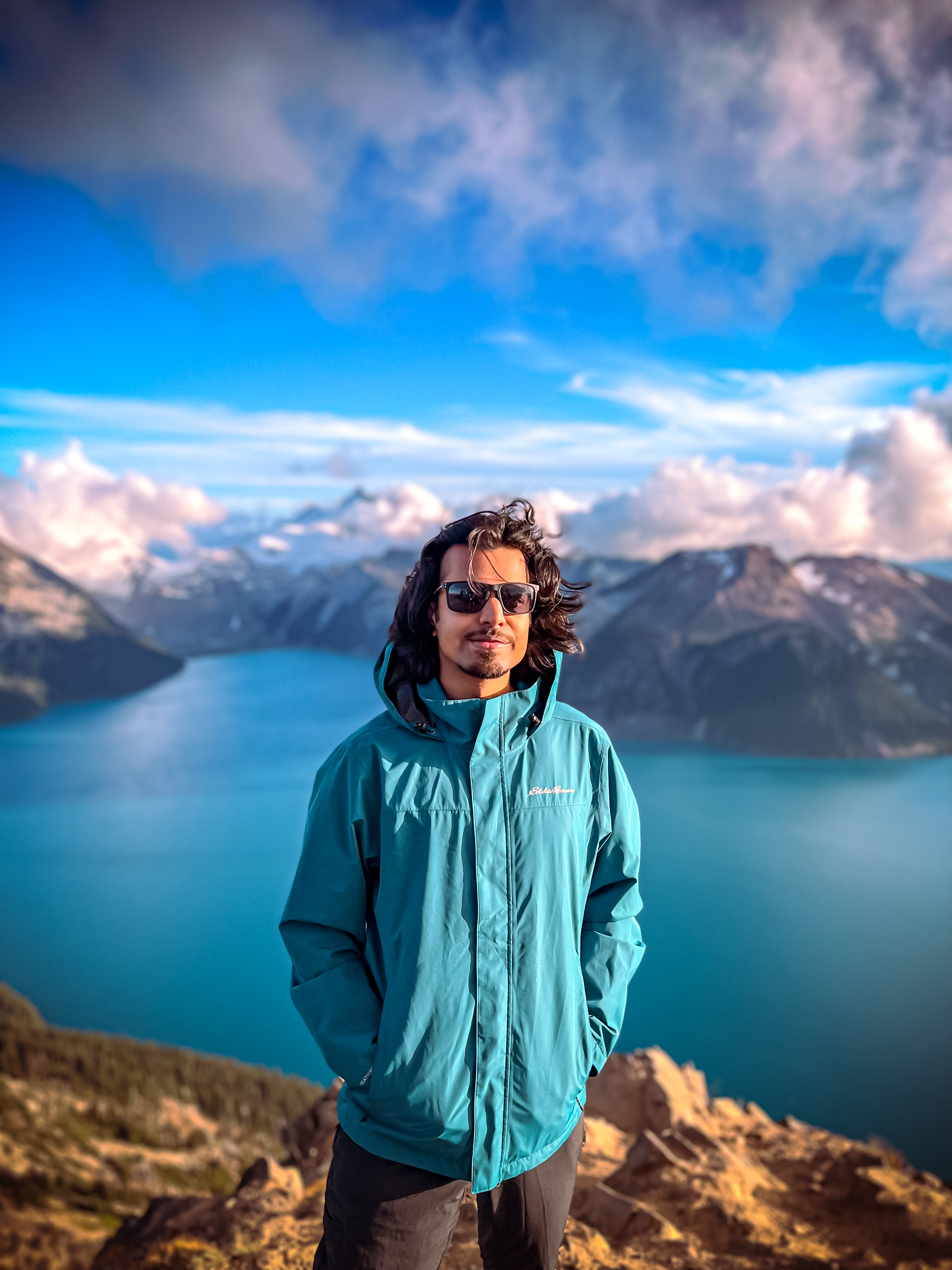Himanshu in the mountains overlooking a turquoise lake