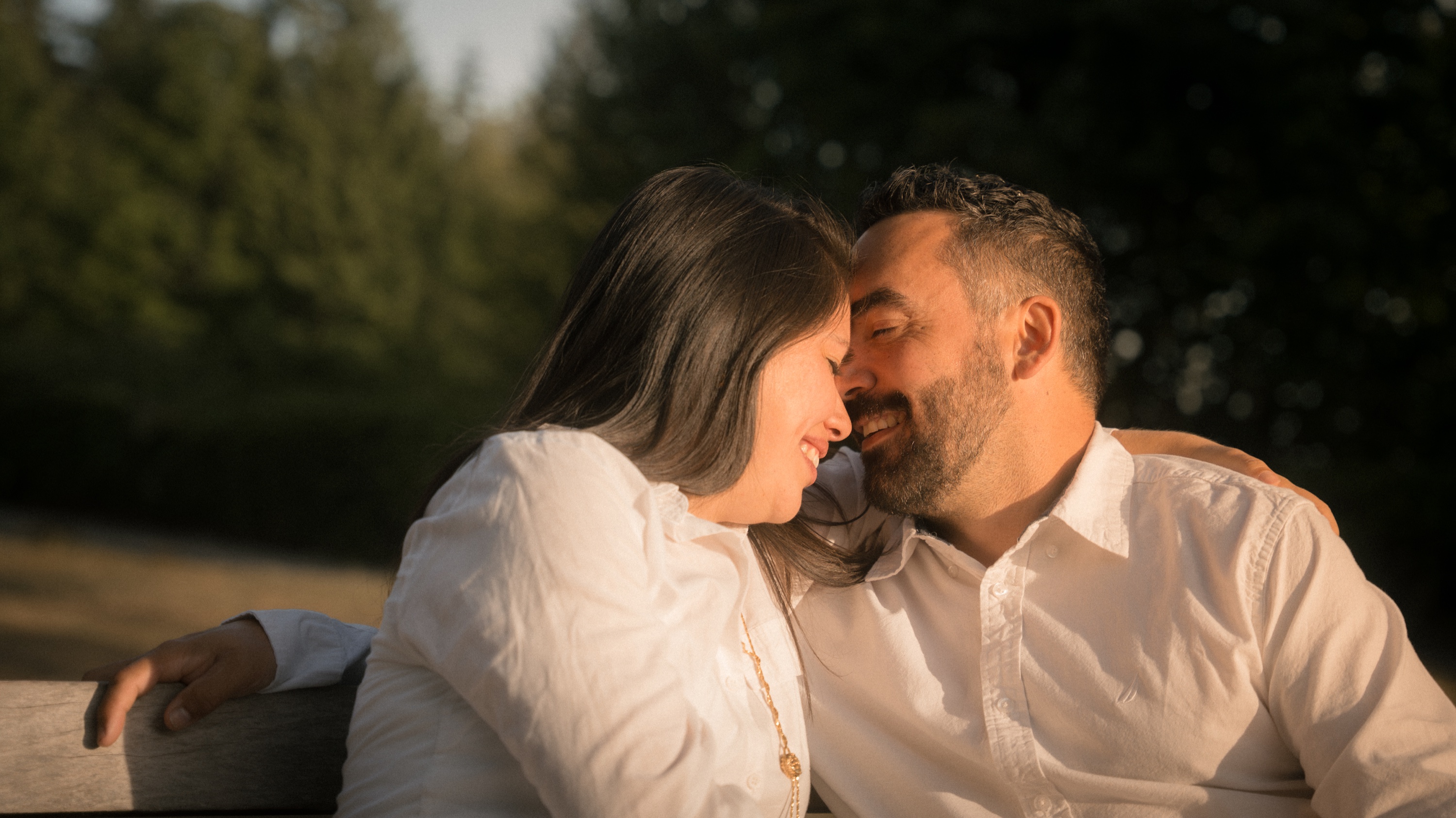 A couple leaning together and smiling on a park bench