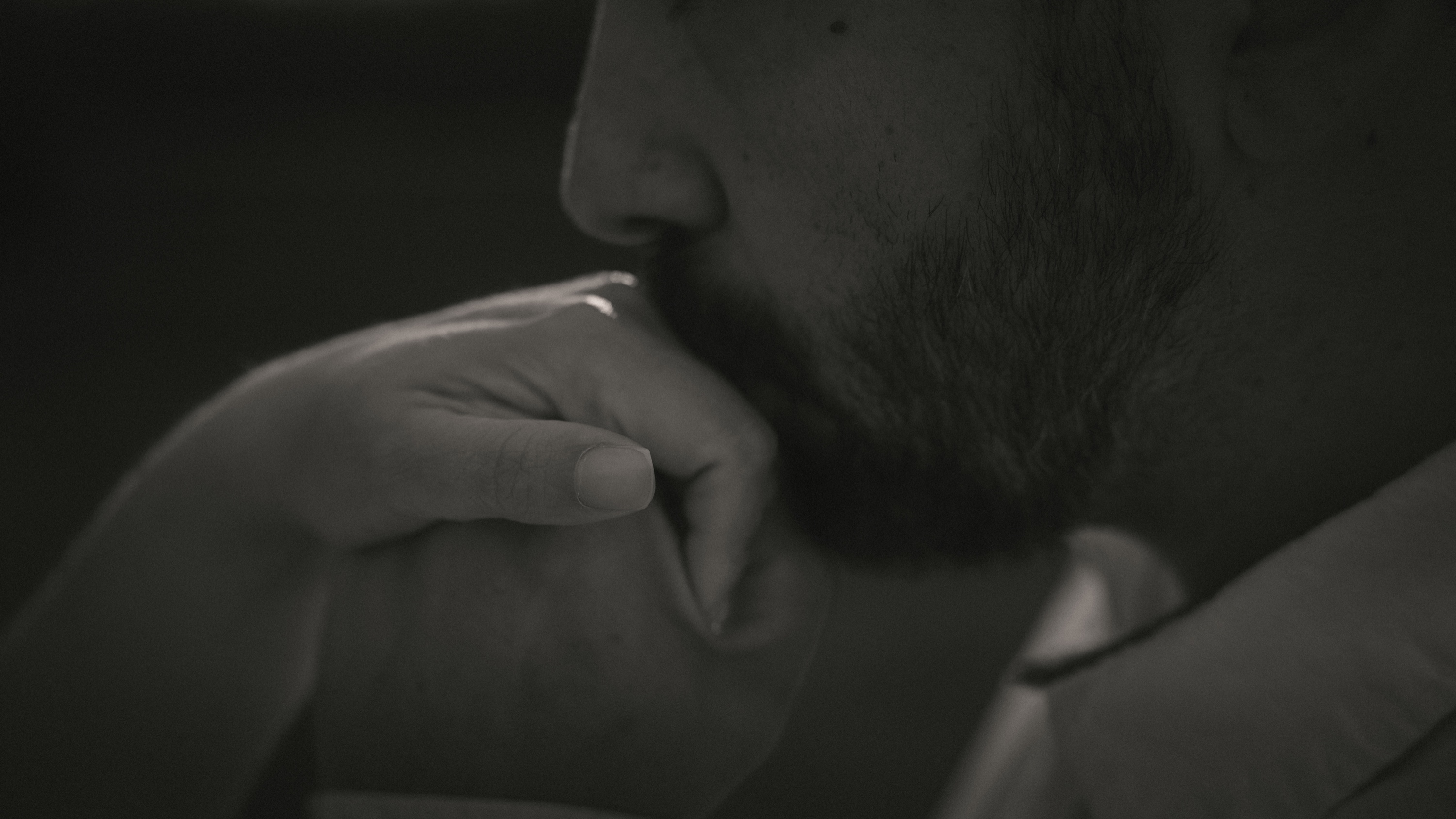 An intimate black and white detail of a hand resting near a face
