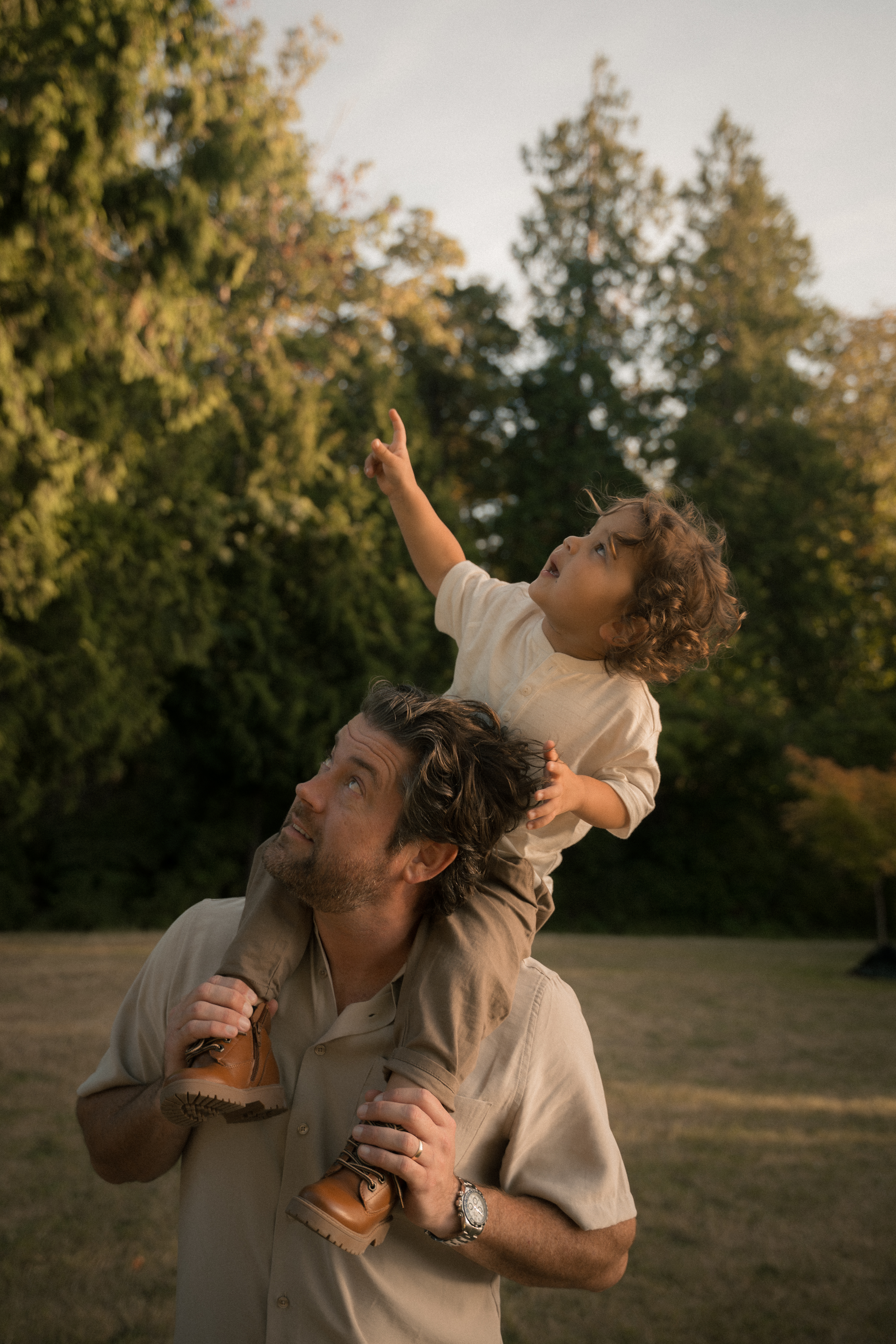 A father carrying his child on his shoulders in warm evening light