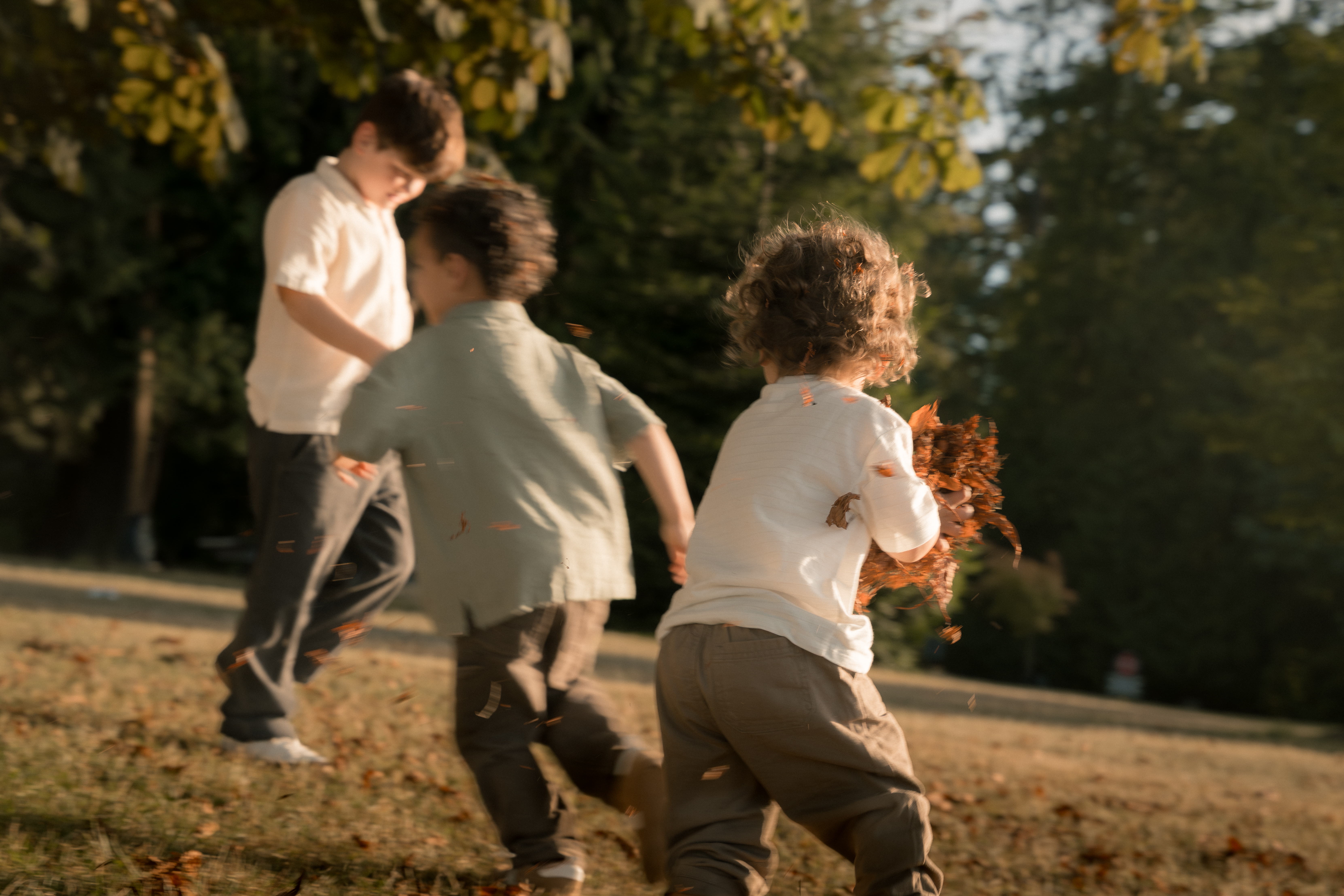 Children racing together through flying leaves in golden light