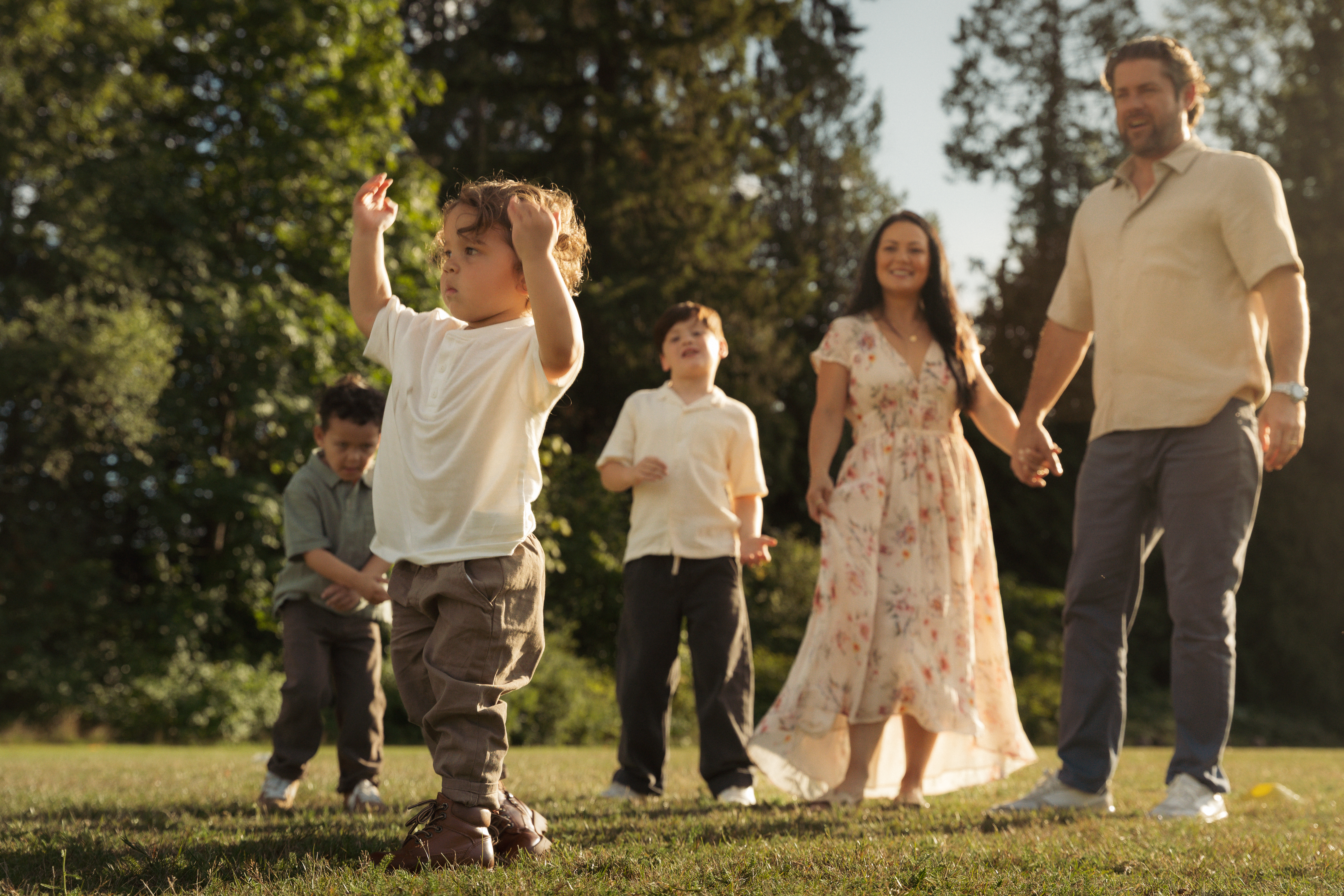 A family walking and playing together in a sunlit park