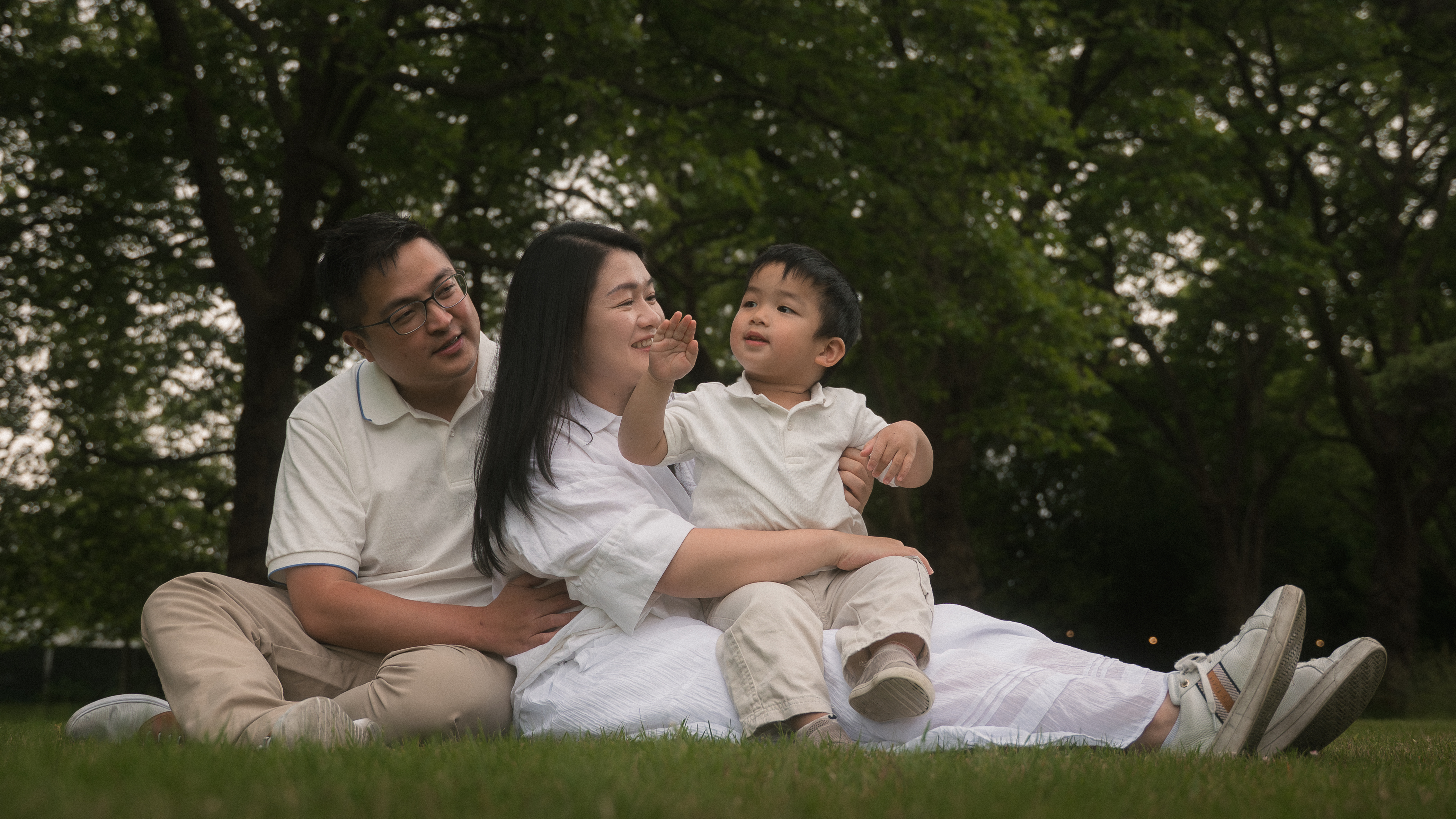A family piled close together on a blanket beneath the trees